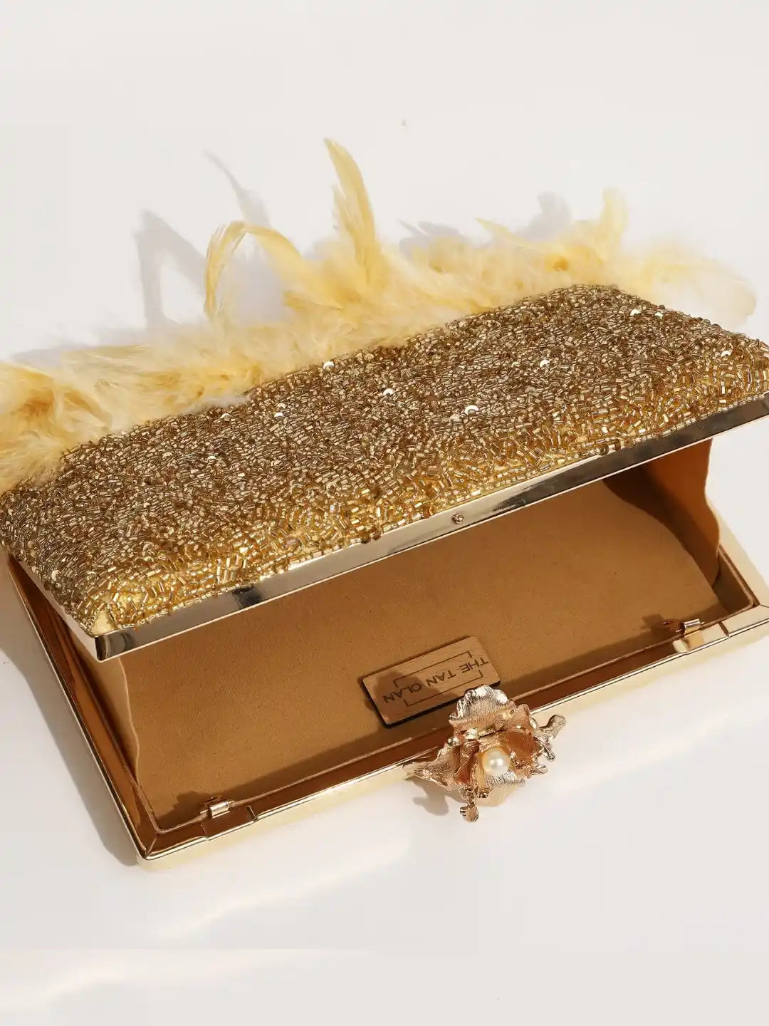 Light gold Daina clutch by The Tan Clan featuring hand embroidery and feather details, stylish evening bag for special occasions.