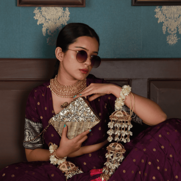 Gold-embellished brass clutch bag with intricate design, featuring a sleek, elegant style suitable for evening occasions.