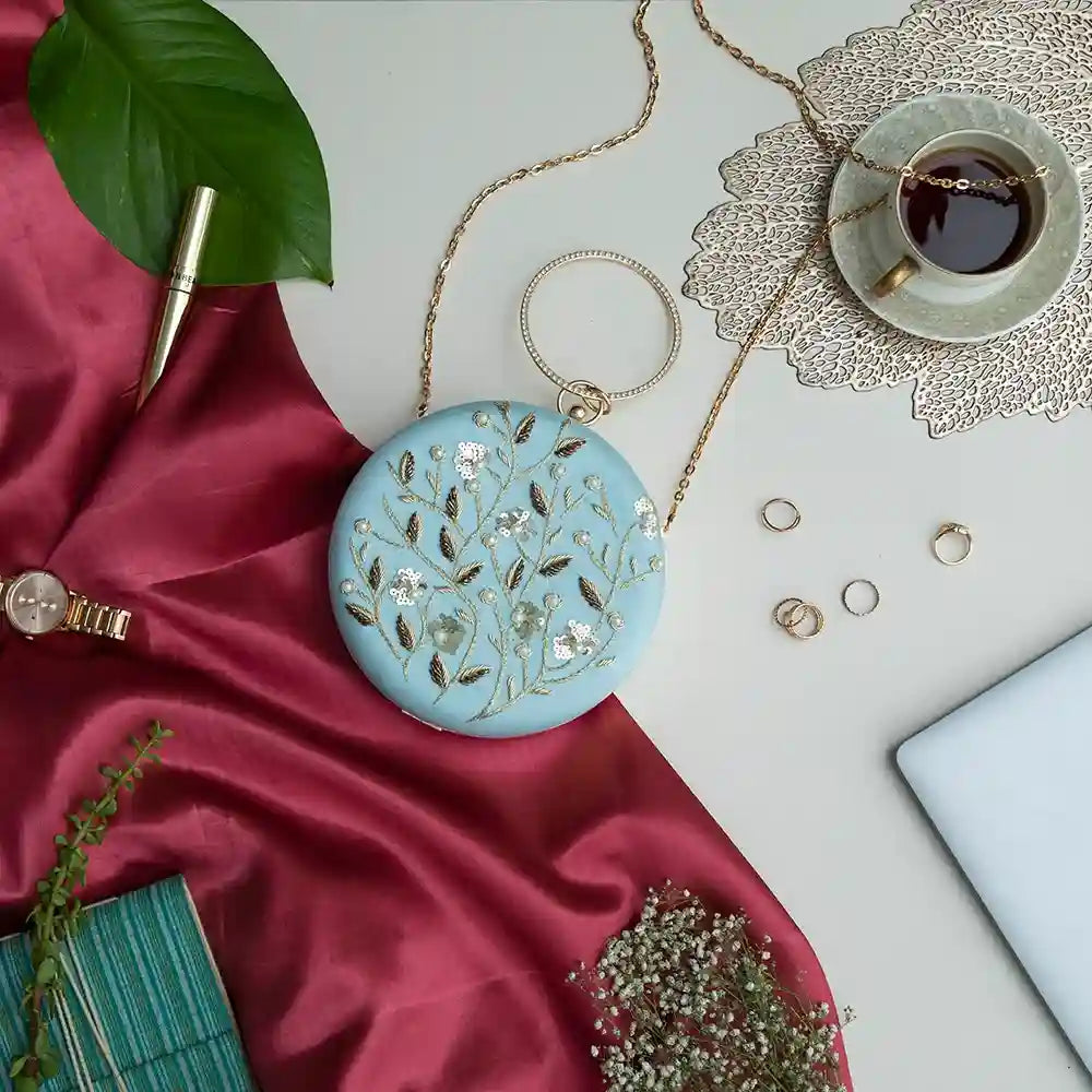 Blue round hand-embroidered clutch bag by The Tan Clan with intricate embroidery and a sleek design.