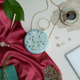 Blue round hand-embroidered clutch bag by The Tan Clan with intricate embroidery and a stylish design.