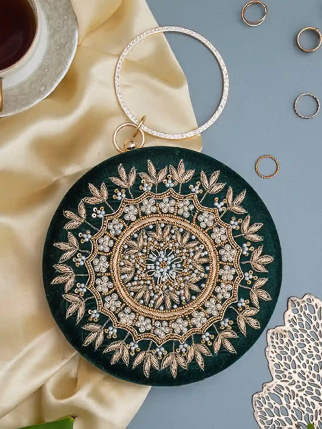 Ifrah green round hand-embroidered clutch by The Tan Clan with intricate embroidery and a vibrant green fabric.