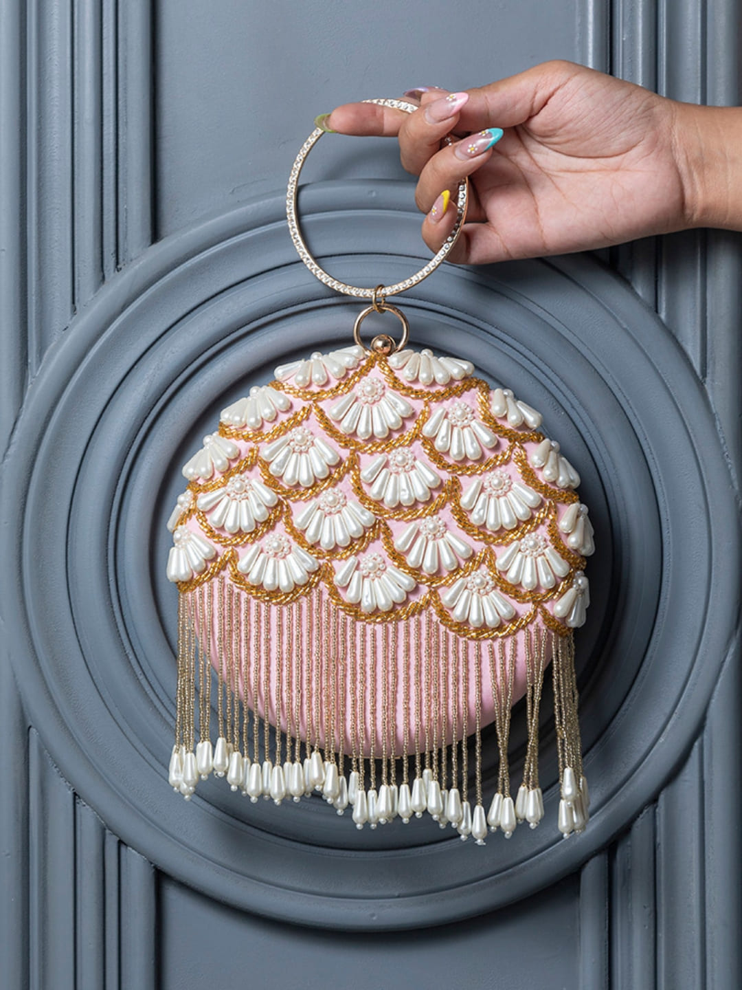 Round hand-embroidered clutch bag with tassels by The Tan Clan featuring intricate embroidery and a stylish design.