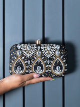 Kalah hand embroidered clutch by The Tan Clan with intricate colorful embroidery on a fabric background.