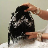 Black tassel potli bag with handle from The Tan Clan, featuring intricate embroidery and a drawstring closure.