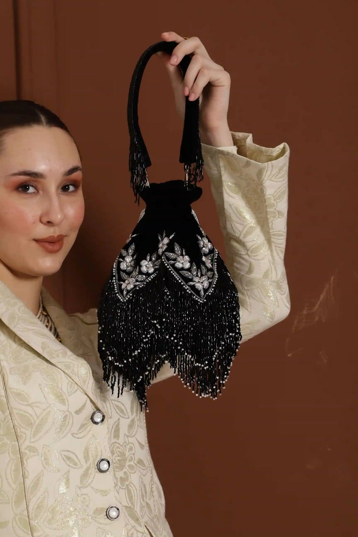 Black tassel potli bag with handle from The Tan Clan, featuring intricate embroidery and a stylish, traditional design.