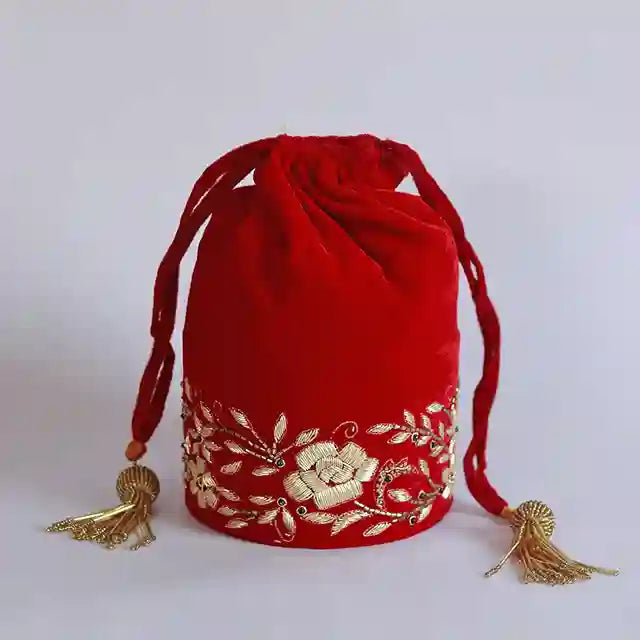 Red bridal Zardozi embroidered potli bag with intricate gold threadwork, traditional accessory for wedding attire.