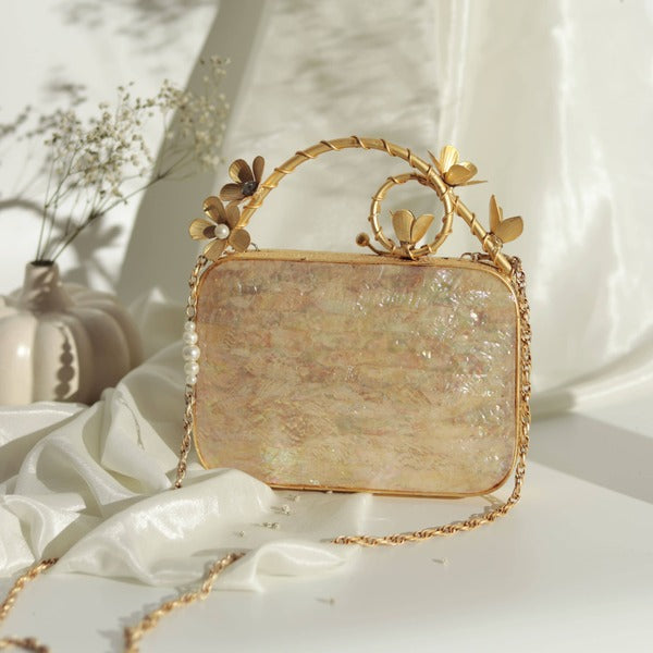 Naira mother of pearl clutch with brass embellished handle, elegant accessory by The Tan Clan, showcasing intricate pearl design and craftsmanship.
