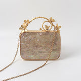 Naira mother of pearl clutch by The Tan Clan with brass-embellished handle, featuring a sleek, elegant design and shimmering surface.