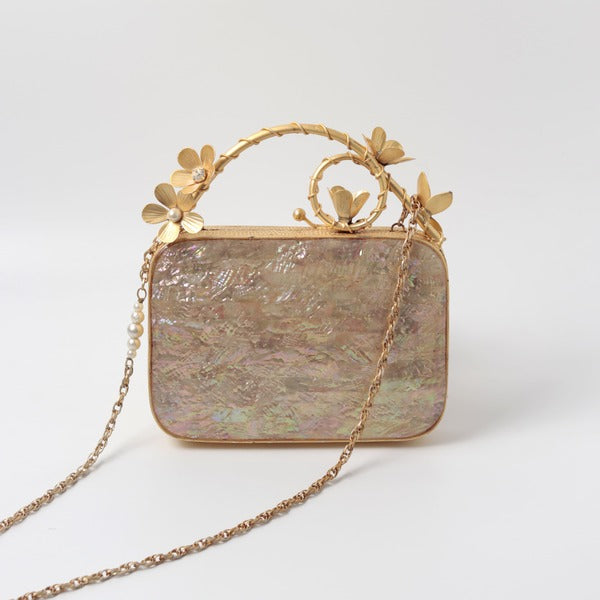 Naira mother of pearl clutch by The Tan Clan with brass embellished handle and elegant pearl detailing on the surface.