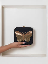 Black square clutch purse by The Tan Clan with hand-embroidered butterfly design and elegant craftsmanship.