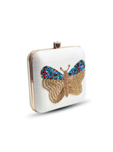 White square clutch by The Tan Clan featuring hand embroidery of colorful butterflies on a fabric surface.