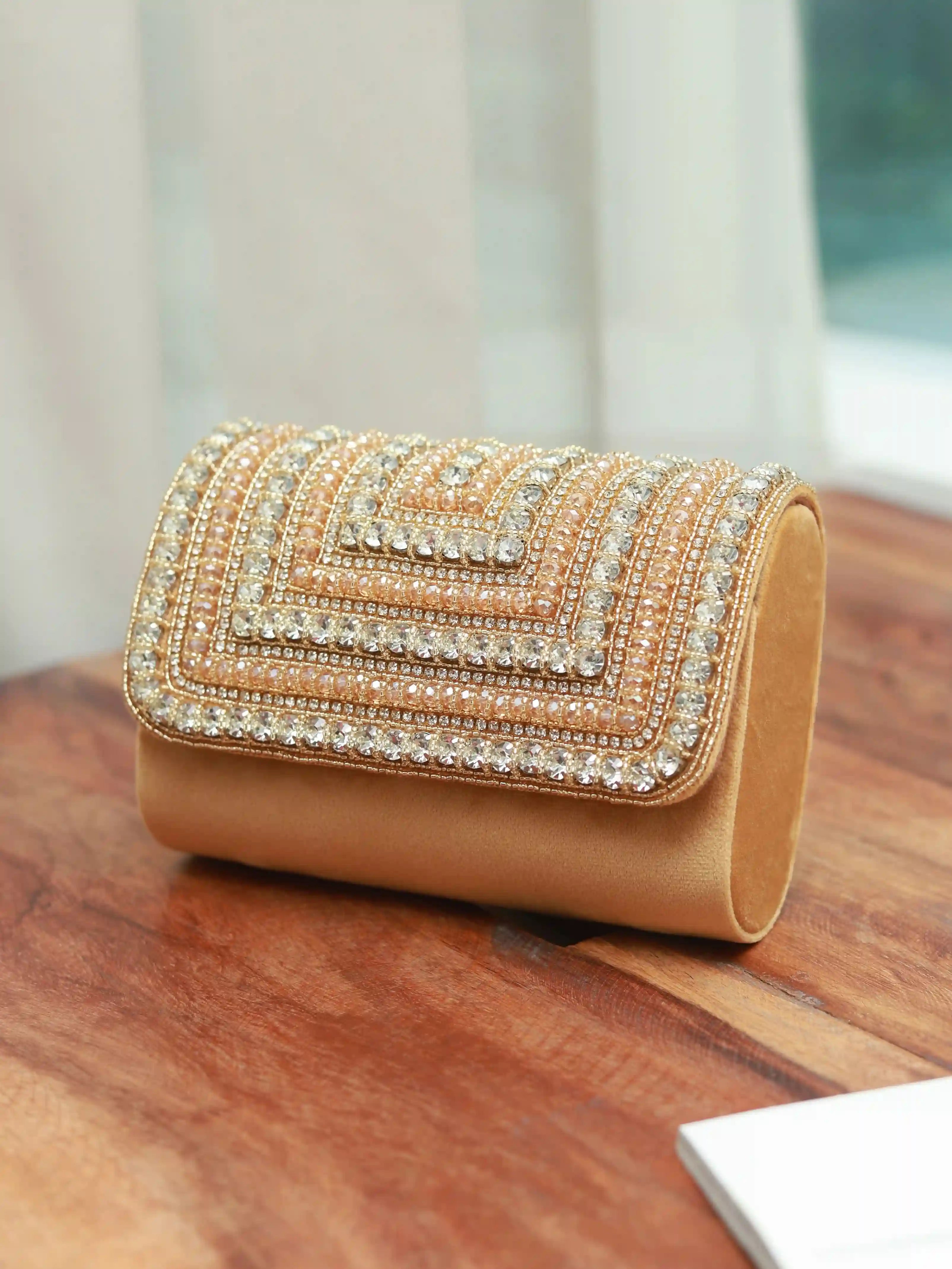 Nysa gold embellished flap-over clutch bag featuring elegant detailing and a sleek design, perfect for evening or formal occasions.