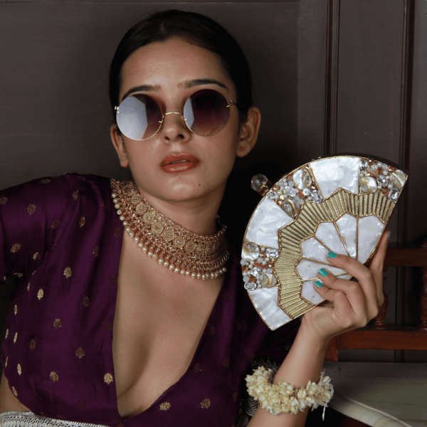 Golden brass mother of pearl clutch bag with intricate design, featuring a sleek rectangular shape and elegant clasp closure.