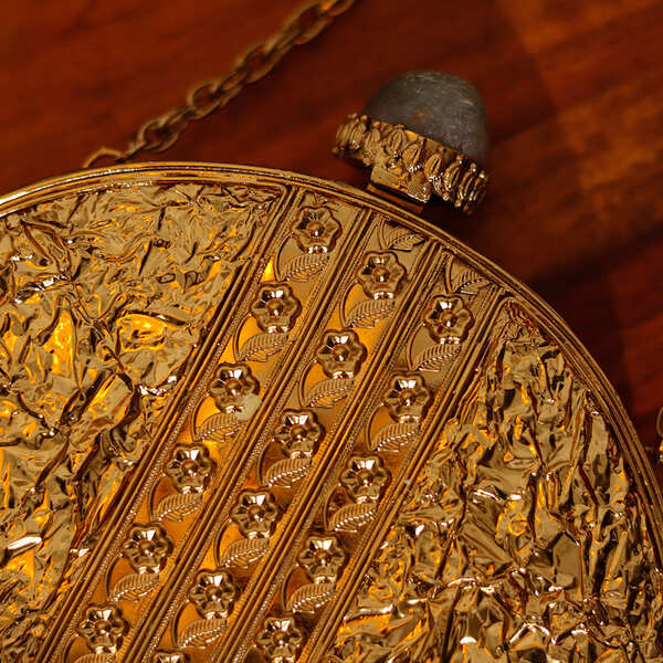 Embellished brass clutch by The Tan Clan featuring intricate designs and a sleek rectangular shape for elegant occasions.