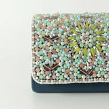 Rainbow embellished flap-over clutch bag by The Tan Clan, featuring colorful rainbow details and a sleek design.