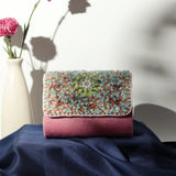 Rainbow embellished flap-over clutch bag by The Tan Clan, featuring colorful rainbow details and a sleek design.