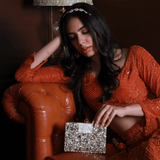 Elegant brass clutch by The Tan Clan with intricate embellishments, featuring a sleek design and decorative details.