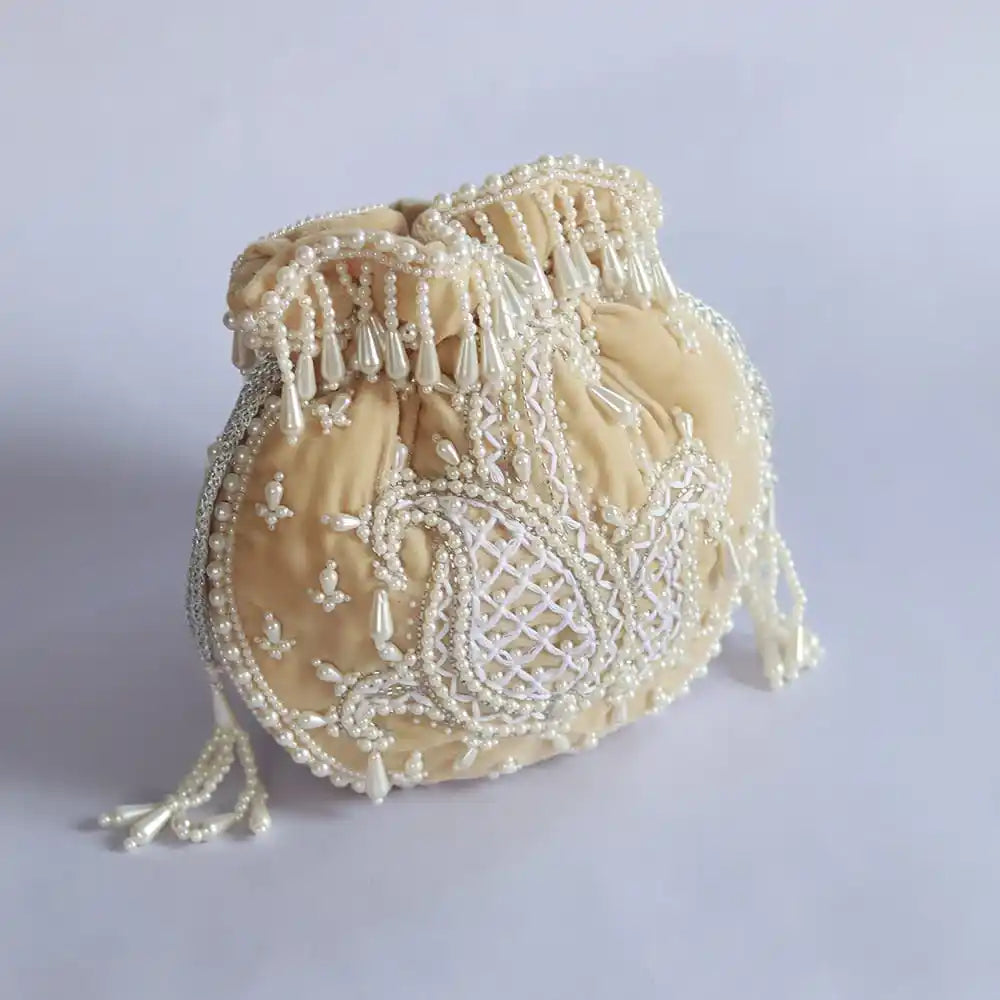 Beige Sukoon hand-embroidered potli bag with pearl handle from The Tan Clan, showcasing intricate embroidery and elegant design.