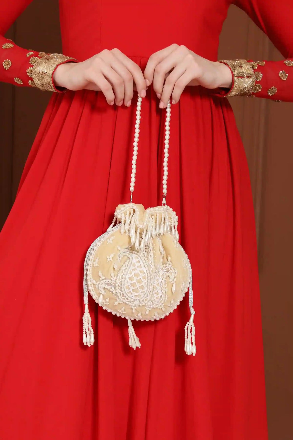 Beige Sukoon hand-embroidered potli bag with pearl handle by The Tan Clan, showcasing intricate embroidery and elegant design.