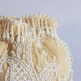Beige Sukoon hand-embroidered potli bag with pearl handle from The Tan Clan, showcasing intricate embroidery and elegant design.