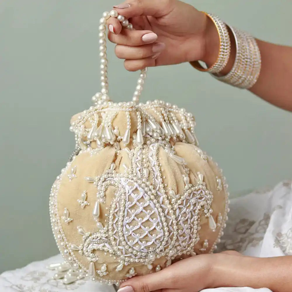 Beige Sukoon hand-embroidered potli bag with pearl handle by The Tan Clan, showcasing intricate embroidery and elegant design.