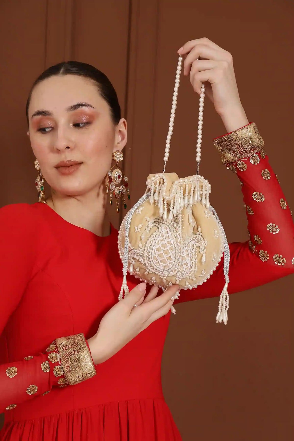 Beige Sukoon hand-embroidered potli bag with pearl handle from The Tan Clan, featuring intricate embroidery and elegant design.