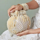 Beige Sukoon hand-embroidered potli bag with pearl handle, crafted by The Tan Clan, featuring intricate embroidery and elegant design.