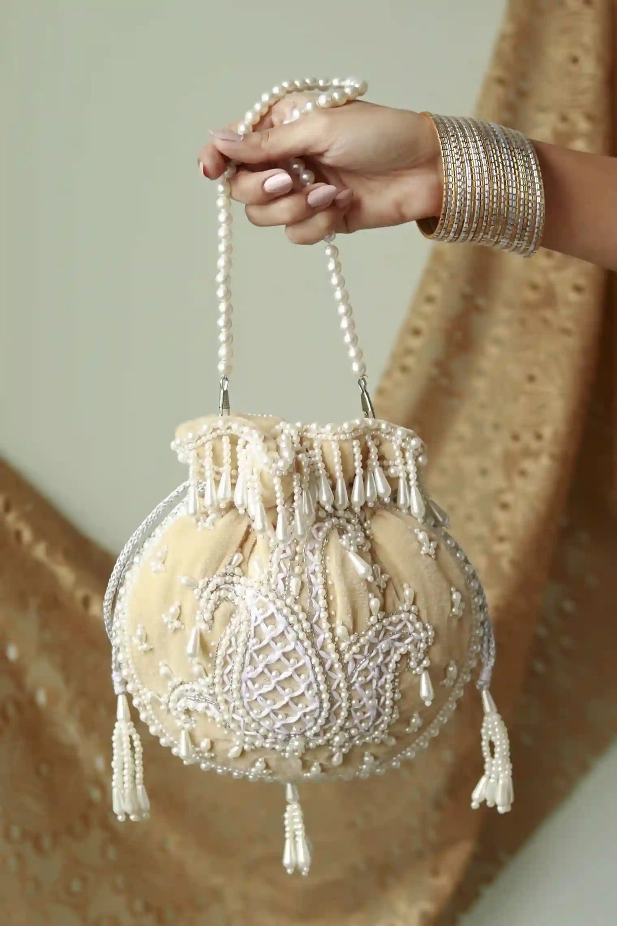 Beige Sukoon hand-embroidered potli bag with pearl handle, featuring intricate embroidery and traditional design by The Tan Clan.
