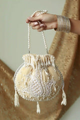 Beige Sukoon hand-embroidered potli bag with pearl handle, featuring intricate embroidery and traditional design by The Tan Clan.