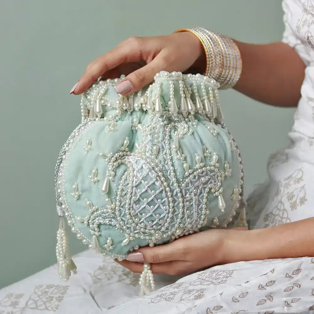 Blue Sukoon hand-embroidered potli bag with pearl handle by The Tan Clan, featuring intricate embroidery and elegant design.