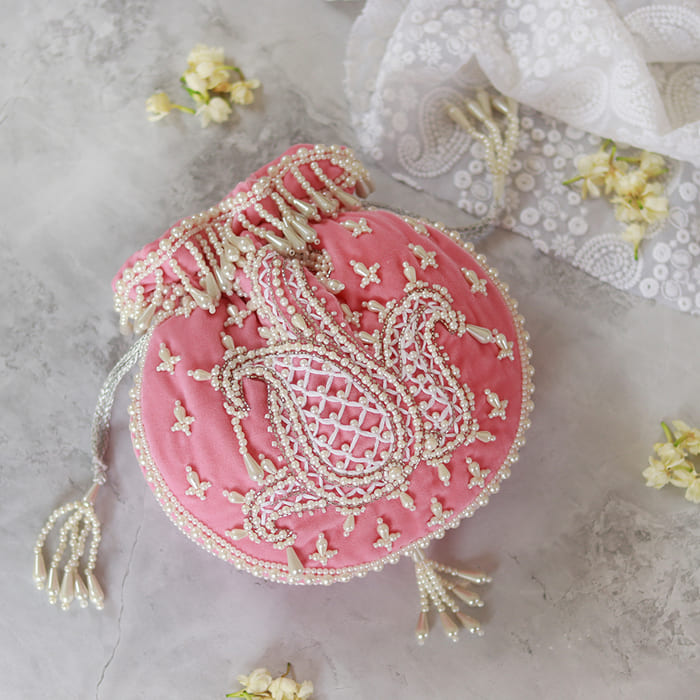 Pink Sukoon hand-embroidered potli bag with pearl handle, crafted by The Tan Clan, featuring intricate embroidery and elegant design.
