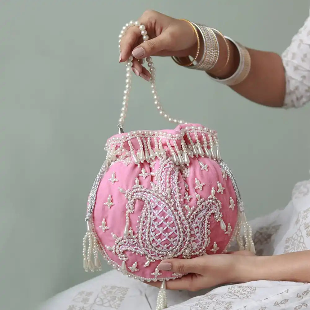 Pink Sukoon hand-embroidered potli bag with pearl handle from The Tan Clan, showcasing intricate embroidery and elegant design.