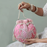 Pink Sukoon hand-embroidered potli bag with pearl handle from The Tan Clan, showcasing intricate embroidery and elegant design.