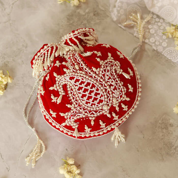 Red Sukoon hand-embroidered potli bag with pearl handle from The Tan Clan, showcasing intricate embroidery and elegant design.
