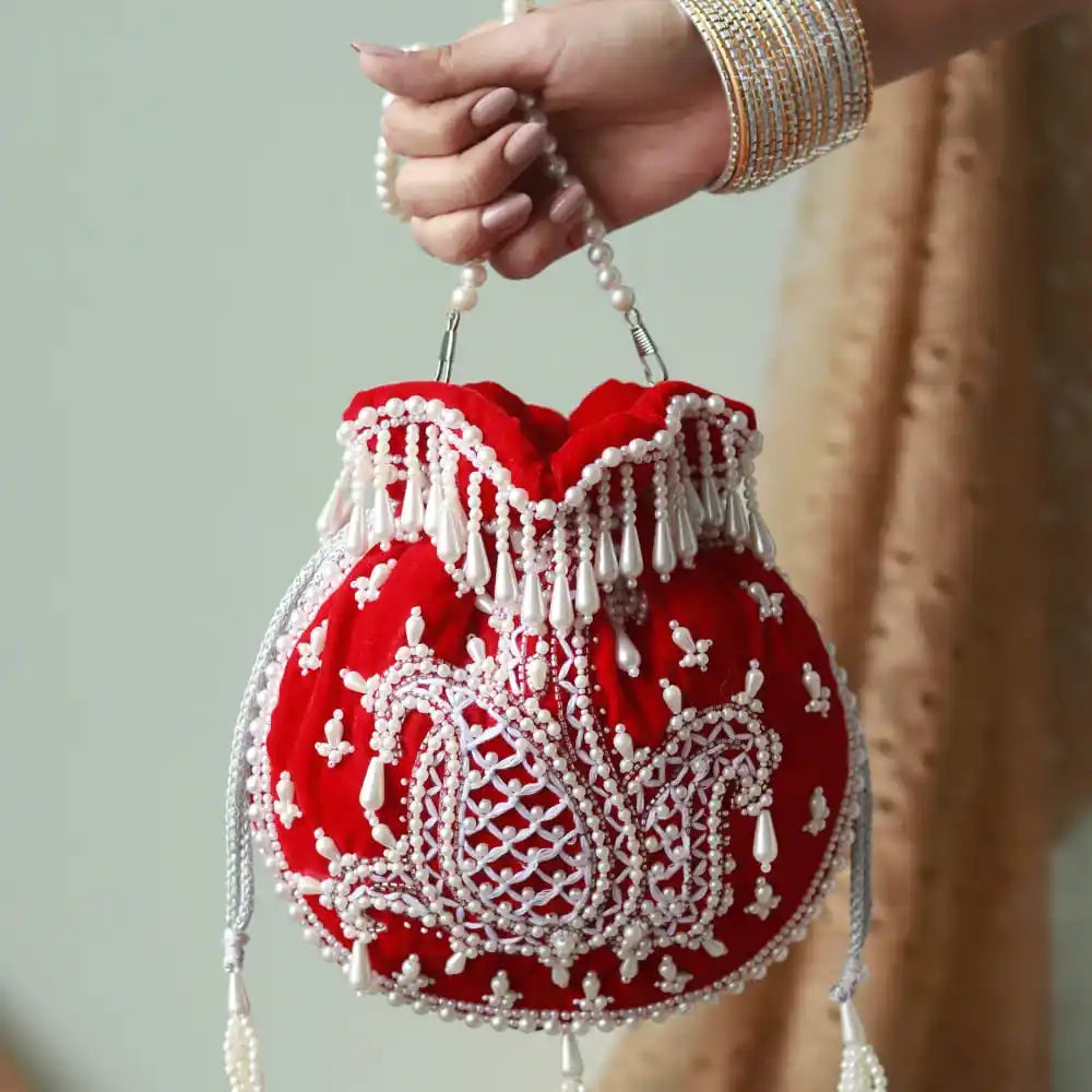 Red Sukoon hand-embroidered potli bag with pearl handle by The Tan Clan, featuring intricate embroidery and elegant design.