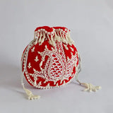 Red Sukoon hand-embroidered potli bag with pearl handle from The Tan Clan, showcasing intricate embroidery and elegant design.