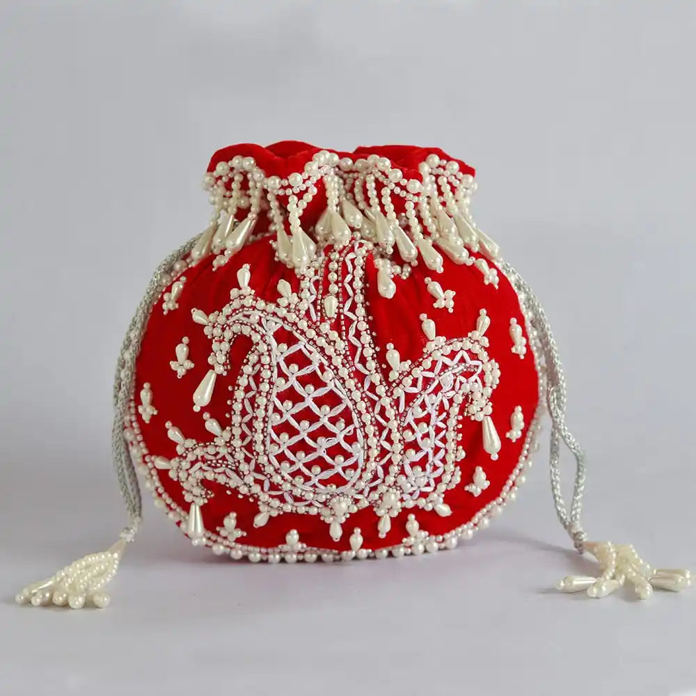 Red Sukoon hand-embroidered potli bag with pearl handle from The Tan Clan, featuring intricate embroidery and elegant design.