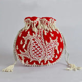 Red Sukoon hand-embroidered potli bag with pearl handle from The Tan Clan, featuring intricate embroidery and elegant design.
