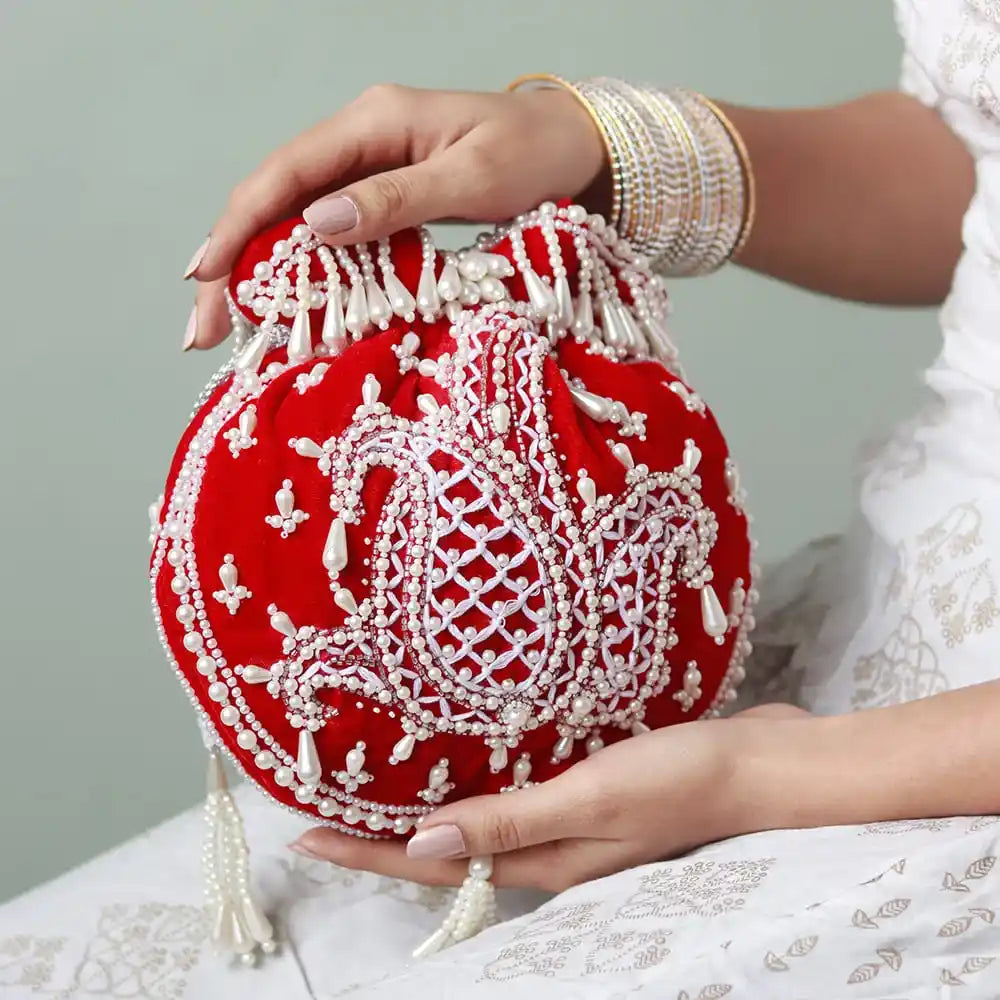 Red Sukoon hand-embroidered potli bag with pearl handle by The Tan Clan, showcasing intricate embroidery and elegant design.