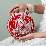 Red Sukoon hand-embroidered potli bag with pearl handle by The Tan Clan, showcasing intricate embroidery and elegant design.