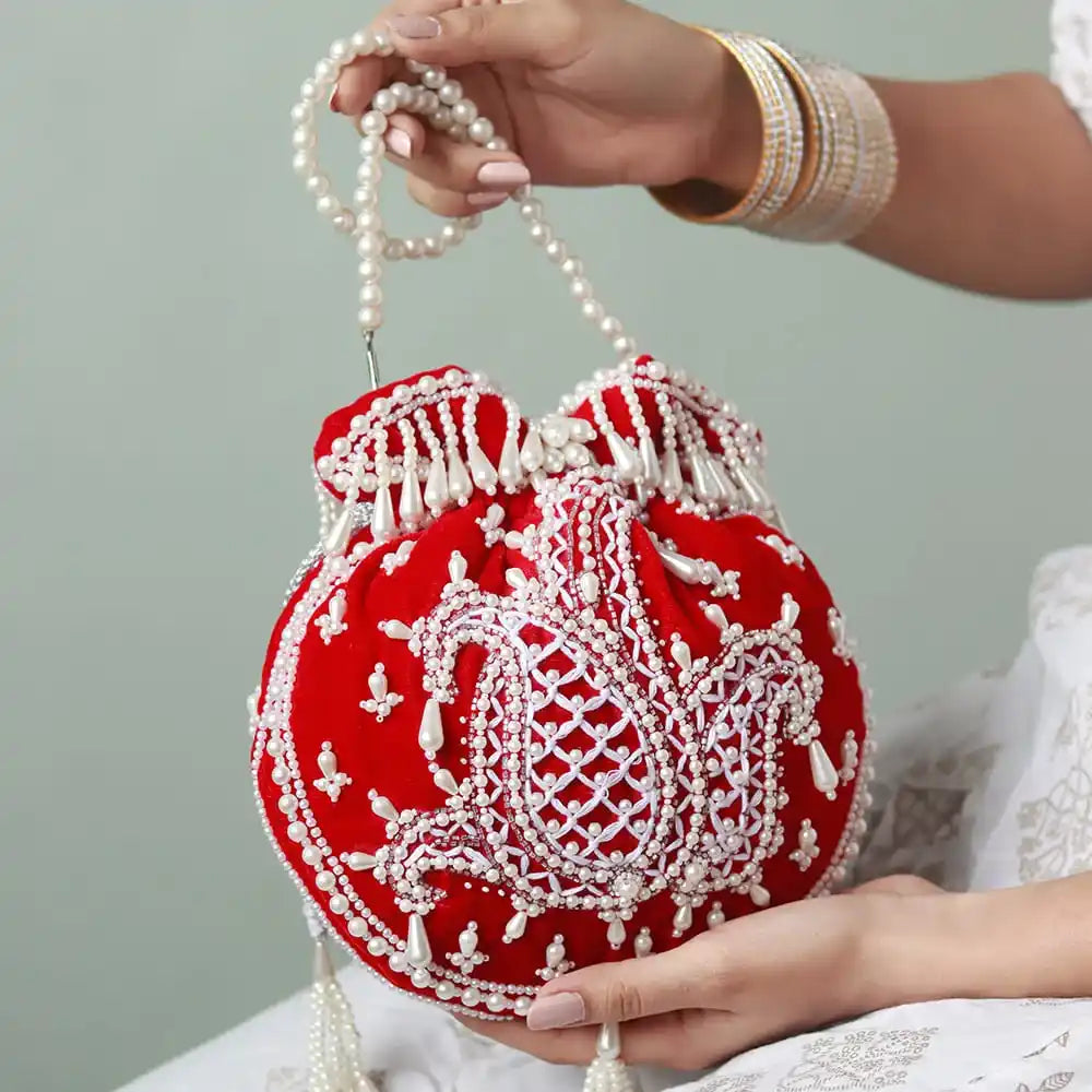 Red Sukoon hand-embroidered potli bag with pearl handle from The Tan Clan, showcasing intricate embroidery and elegant design.
