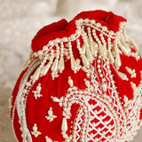 Red Sukoon hand-embroidered potli bag with pearl handle from The Tan Clan, showcasing intricate embroidery and elegant design.