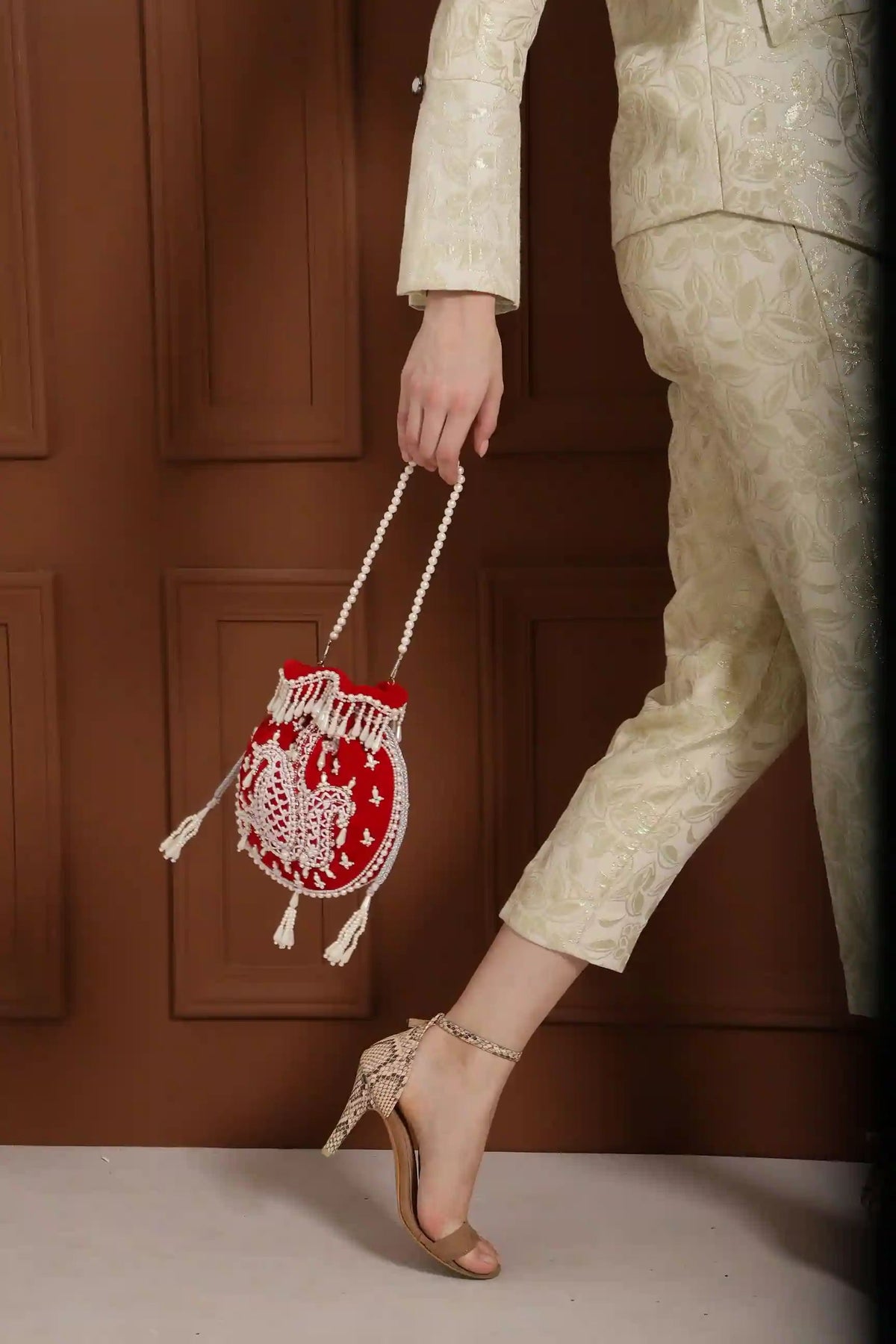 Red Sukoon hand-embroidered potli bag with pearl handle by The Tan Clan, showcasing intricate embroidery and elegant design.