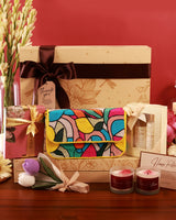 Luxury hamper from The Tan Clan featuring a decorative arrangement with flowers, soft fabrics, and gourmet treats in elegant packaging.