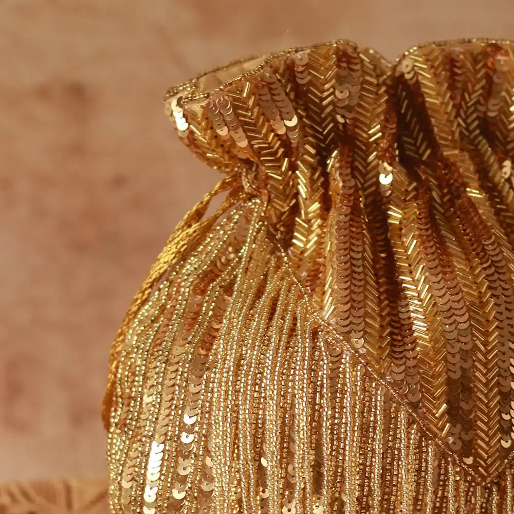 Gold Twinkle Heavy Tassles Potli bag with handle by The Tan Clan, featuring decorative tassels and elegant design.