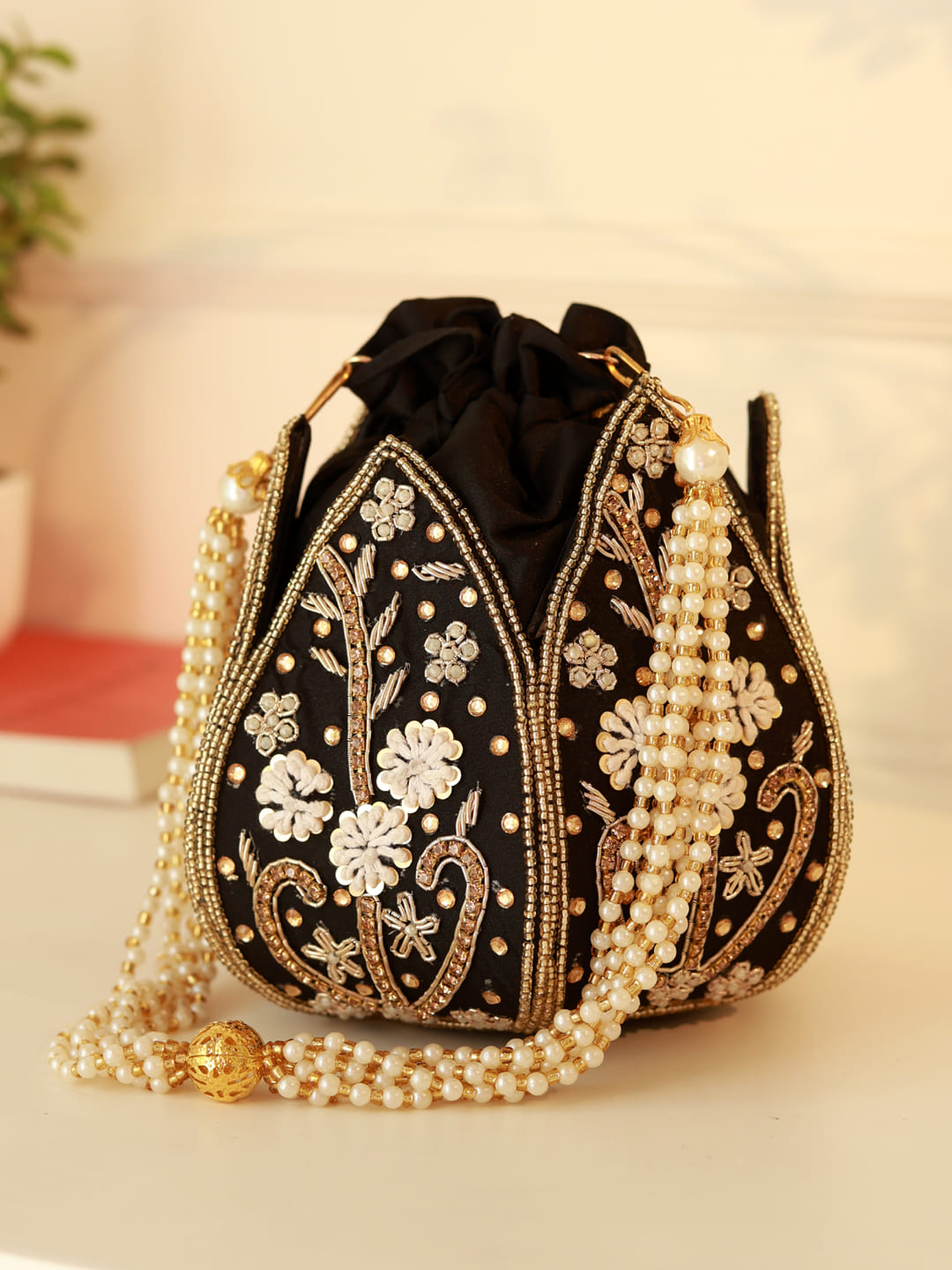 Black Lotus Potli bag from The Tan Clan, traditional Indian-style potli with intricate detailing and tassels.