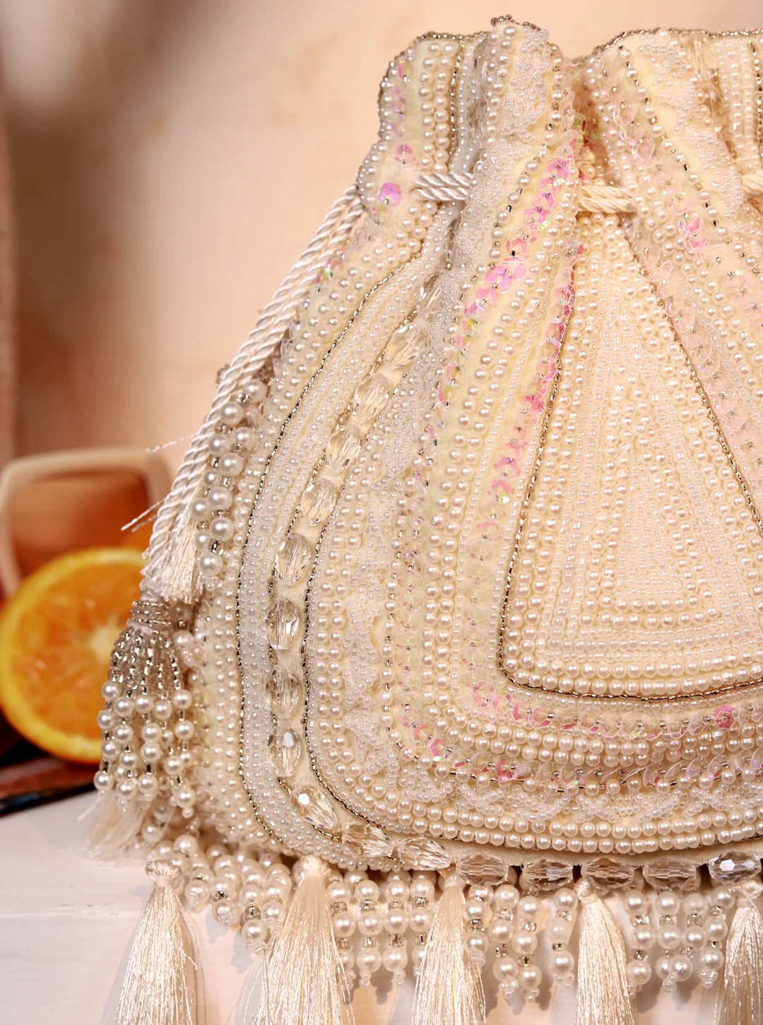 Nora White Tasselled Potli Bag from The Tan Clan featuring white fabric with decorative tassels and traditional design.