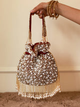 Red pearl potli bag with tassels from The Tan Clan, featuring intricate design and traditional Indian style.